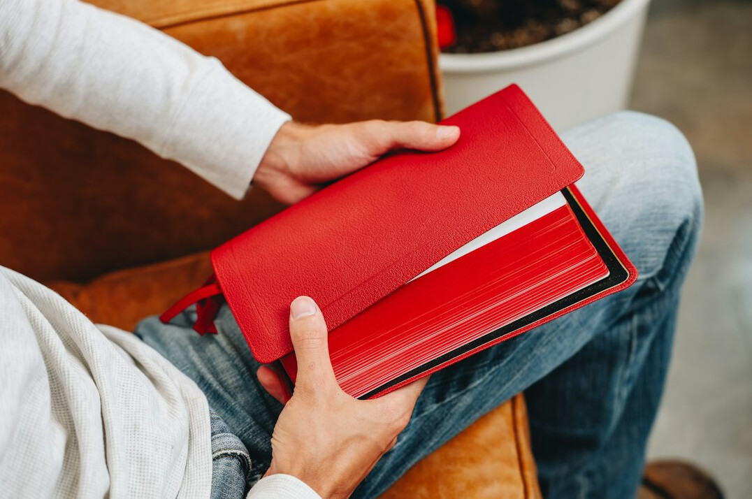 Hand writing notes in a notebook next to a laptop